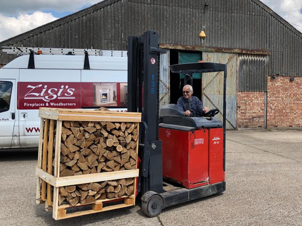 A man driving a fork lift with a log pallett